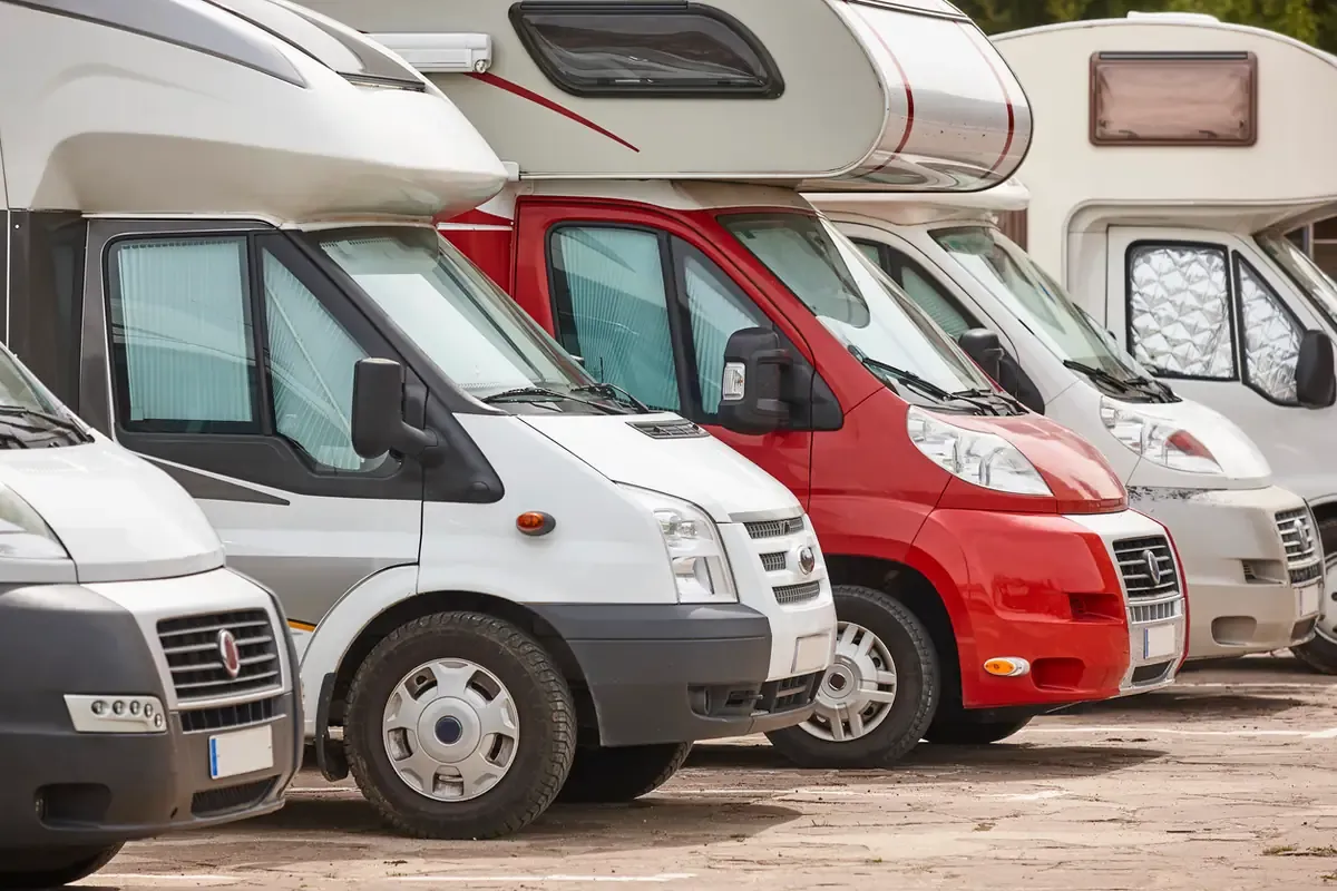 RVs parked in a row at an outdoor storage lot.